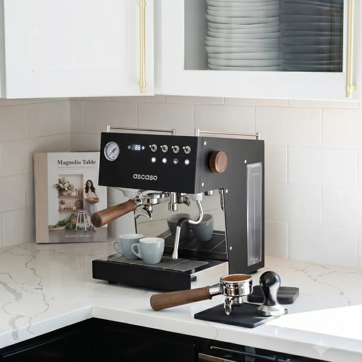 Ascaso Steel Duo V2.5 PID Dual Thermoblock Espresso Machine in black, on a marble kitchen counter with cups and a tamper