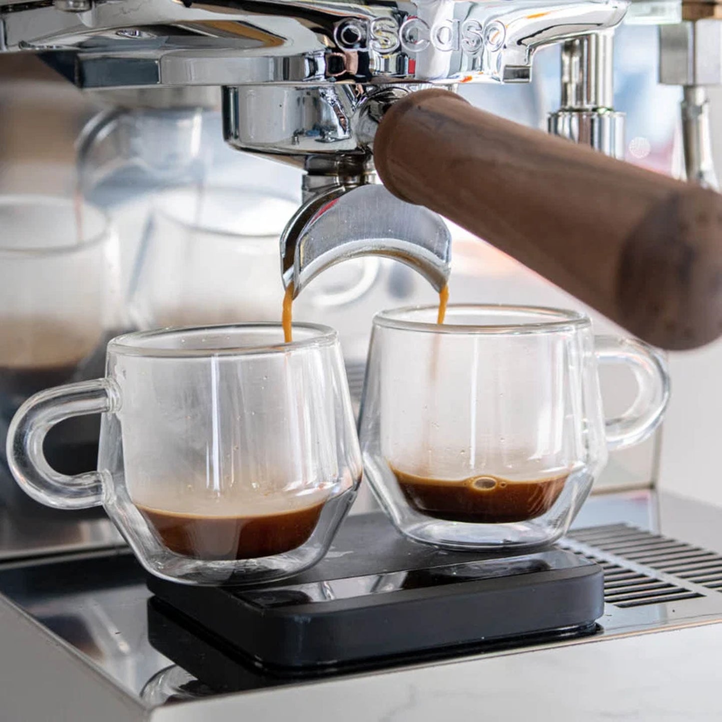 Ascaso Steel Duo V2.5 PID Dual Thermoblock Espresso Machine in white, espresso extracting into two glass cups on a scale