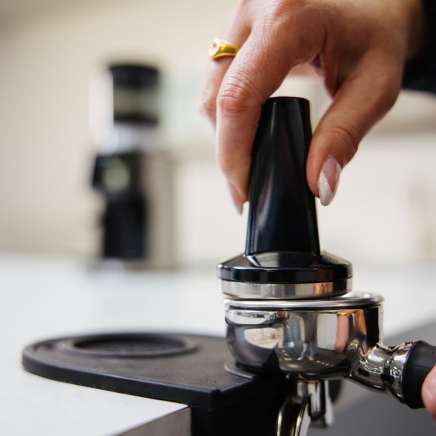 Bellucci Casa Coffee Grinder in black, tamping ground coffee in a portafilter