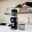Bellucci Casa Coffee Grinder in black, grinding into a portafilter on a kitchen counter