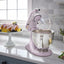 KitchenAid Artisan Series 5-Quart Tilt-Head Stand Mixer in wildflower, on a kitchen counter beside a bowl of fruit