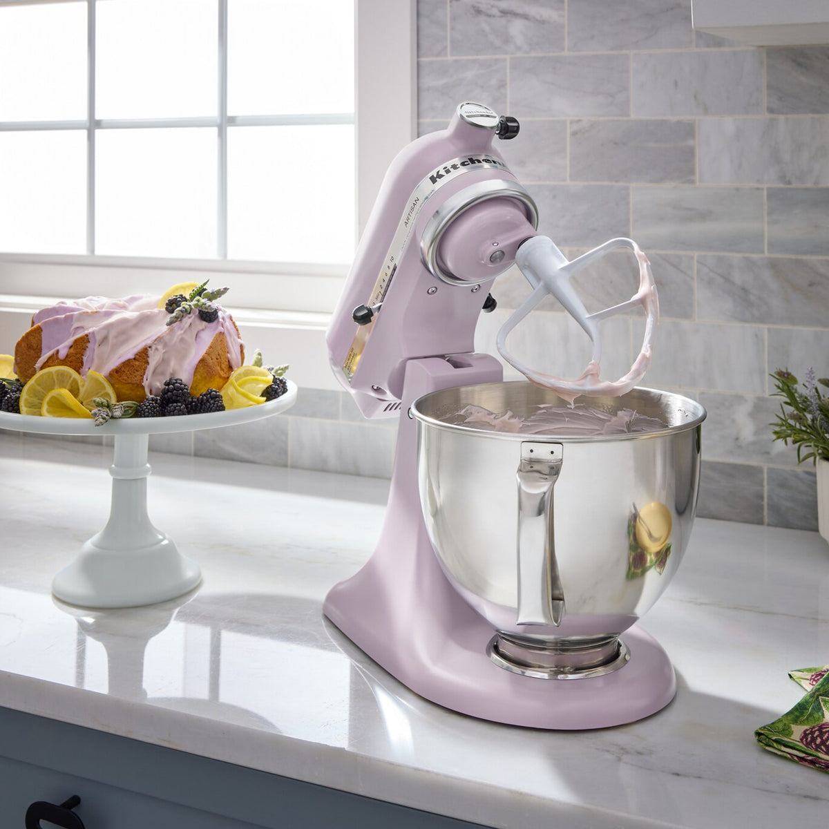 KitchenAid Artisan Series 5-Quart Tilt-Head Stand Mixer in wildflower, on a kitchen counter beside a bowl of fruit