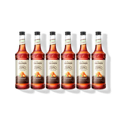Six 750ml glass bottles of Monin Natural Zero Caramel syrup in a row