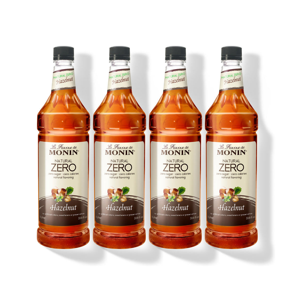 Four 1L plastic bottles of Monin Natural Zero Hazelnut syrup in a row