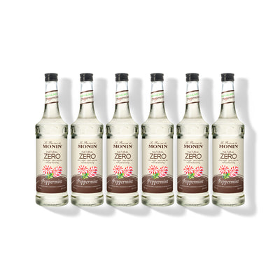 Six 750ml glass bottles of Monin Natural Zero Peppermint syrup in a row