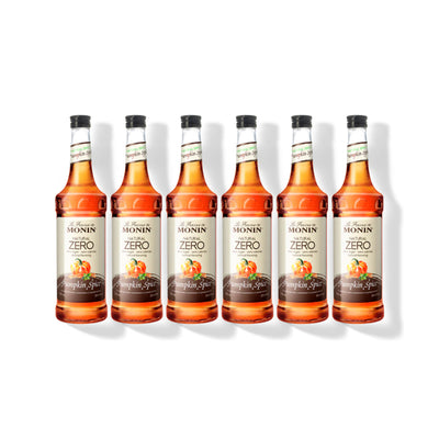 Six 750ml glass bottles of Monin Natural Zero Pumpkin Spice syrup in a row