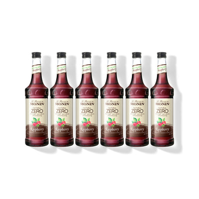 Six 750ml glass bottles of Monin Natural Zero Raspberry syrup in a row