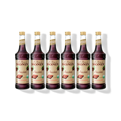 Six 750ml glass bottles of Monin Organic Chocolate syrup in a row