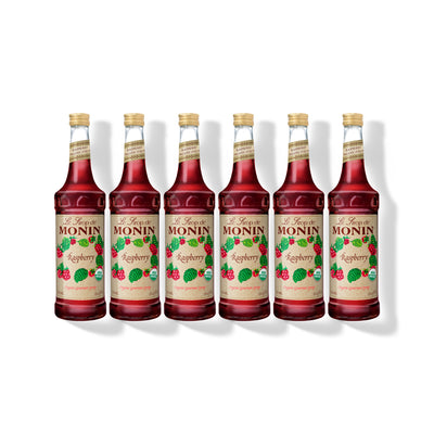 Six 750ml glass bottles of Monin Organic Raspberry syrup in a row