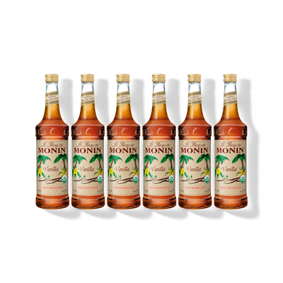 Six 750ml glass bottles of Monin Organic Vanilla syrup in a row
