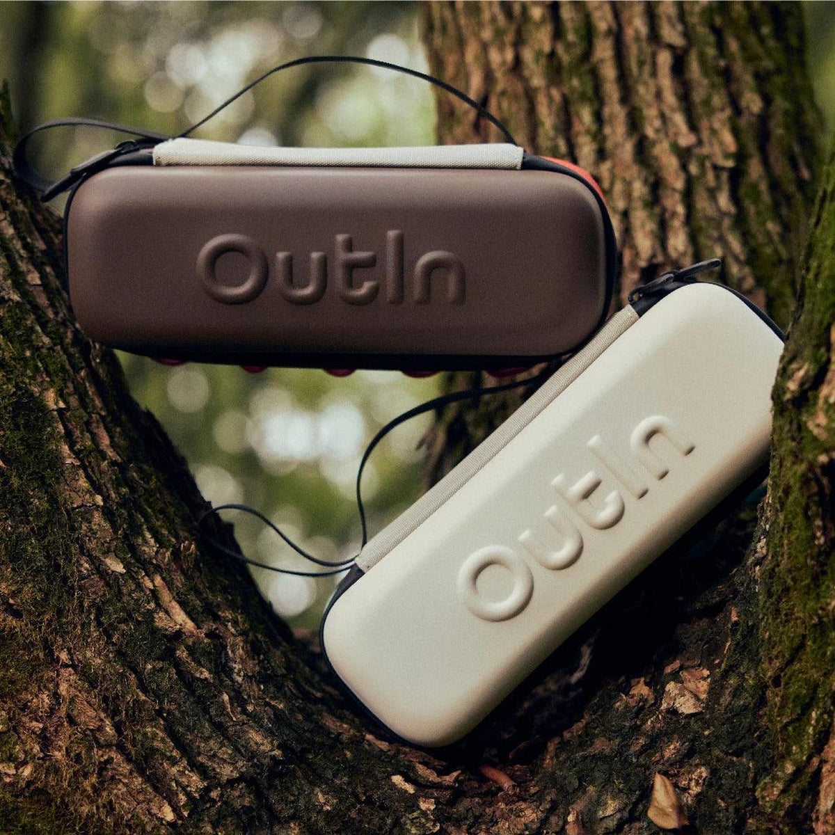 OutIn EVA Protective Case in maple brown, resting in a tree beside the sand beige case