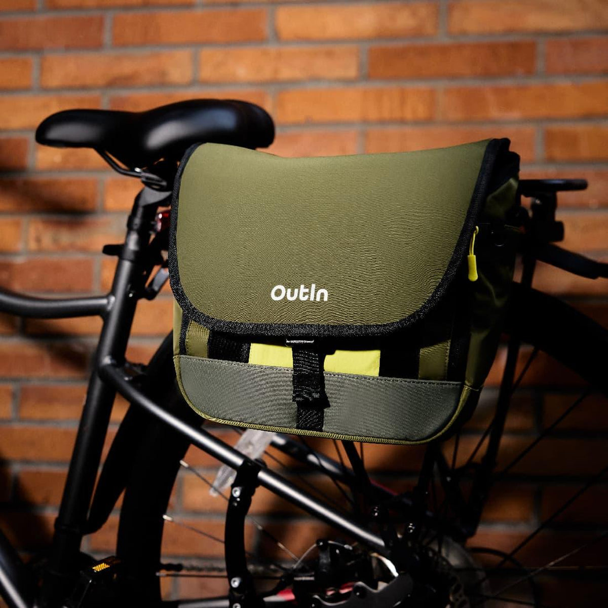 OutIn Flex Messenger Bag in cypress green, mounted on a bicycle rack